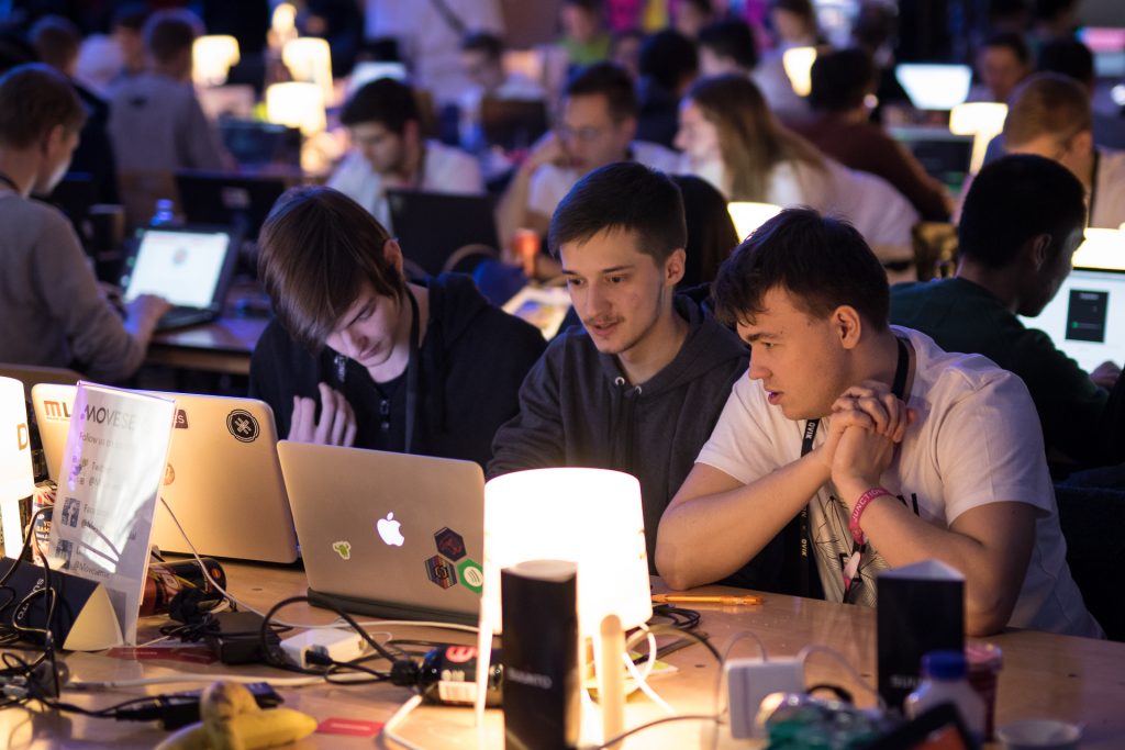 A team of three hackers watching a PC screen, concentrating on their project.